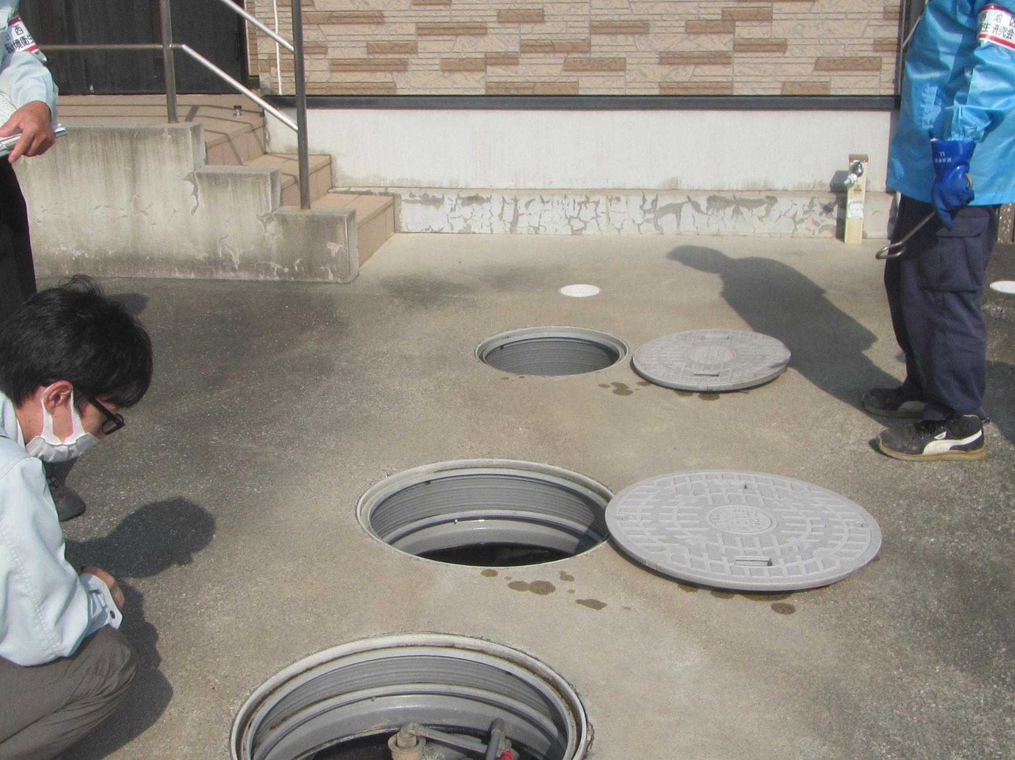 建築物付近の浄化槽を視る職員の写真