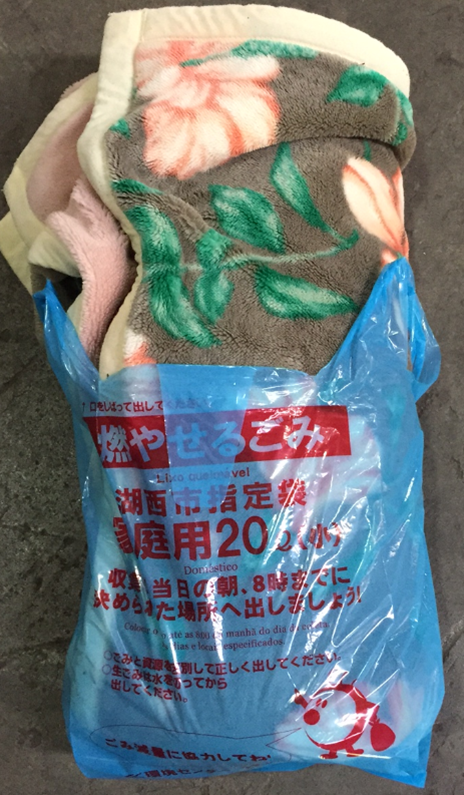 可燃ごみ用ゴミ袋に納まりきらない毛布の廃棄物の写真