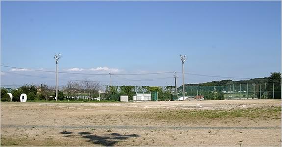 青空の下、緑に囲まれたとても広い運動広場の写真