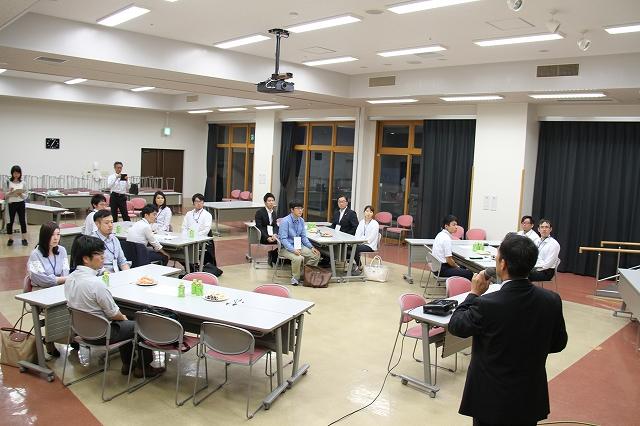 マイクを使って話している人に耳を傾けている参加者の写真