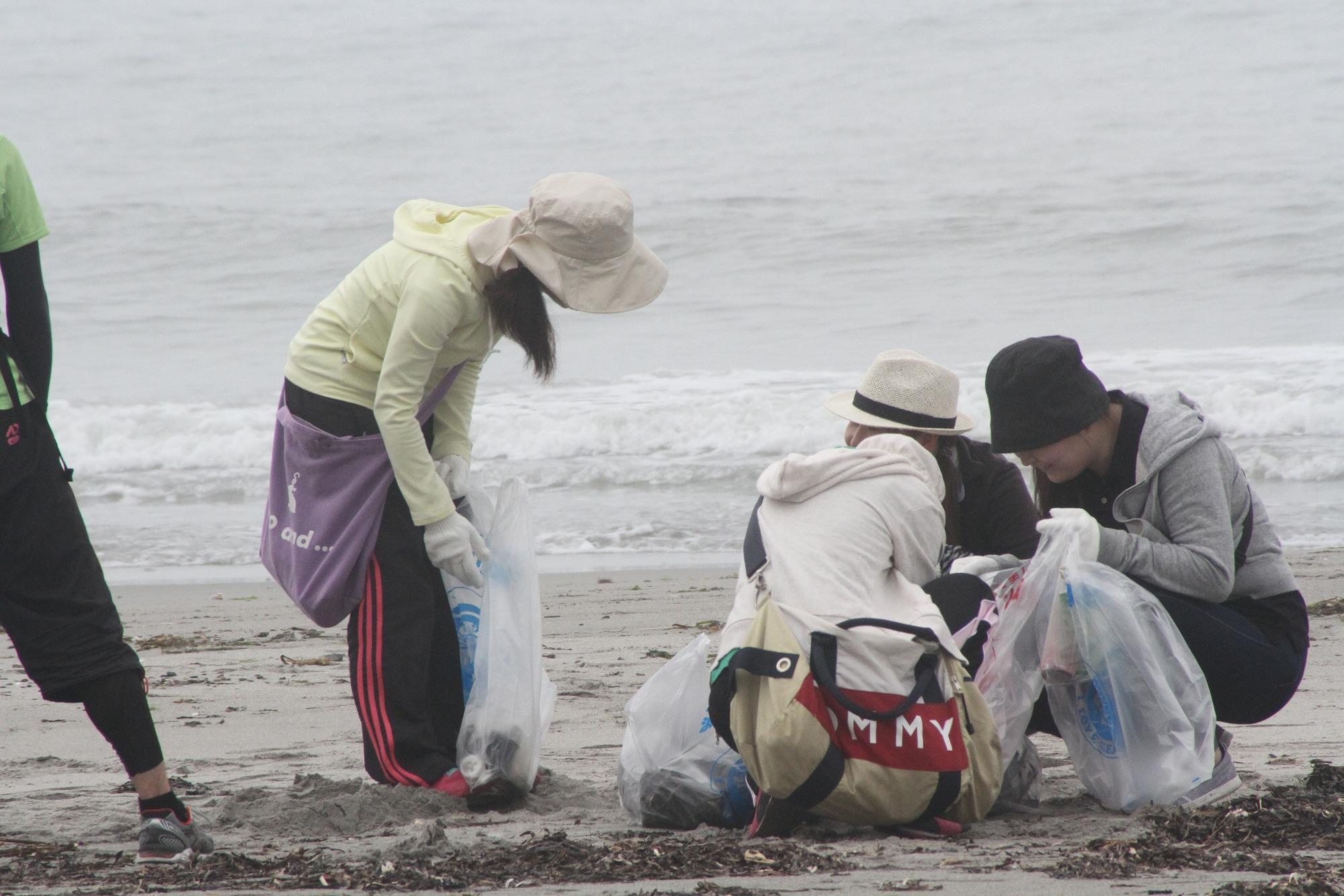 帽子にジャージ、軍手をしてゴミ袋も持って浜名湖の砂地のゴミ拾いをしている写真
