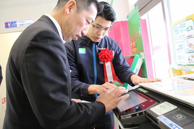 影山市長が店舗内に設置されている多機能端末機で説明を受けながら印鑑登録証明書を取得している様子の写真