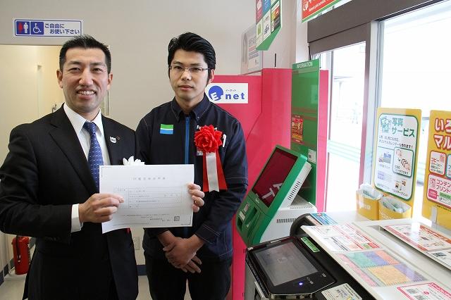 取得した印鑑証明を持った影山市長とファミリーマート鷲津駅前店店長の記念写真